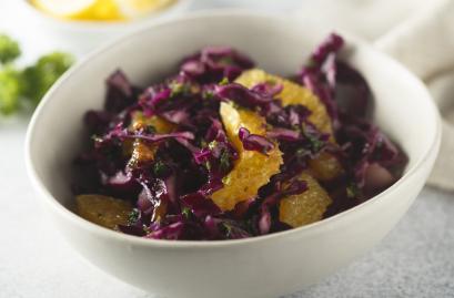 Frischer Rotkohlsalat mit Orangenstücken in einer weißen Schale.