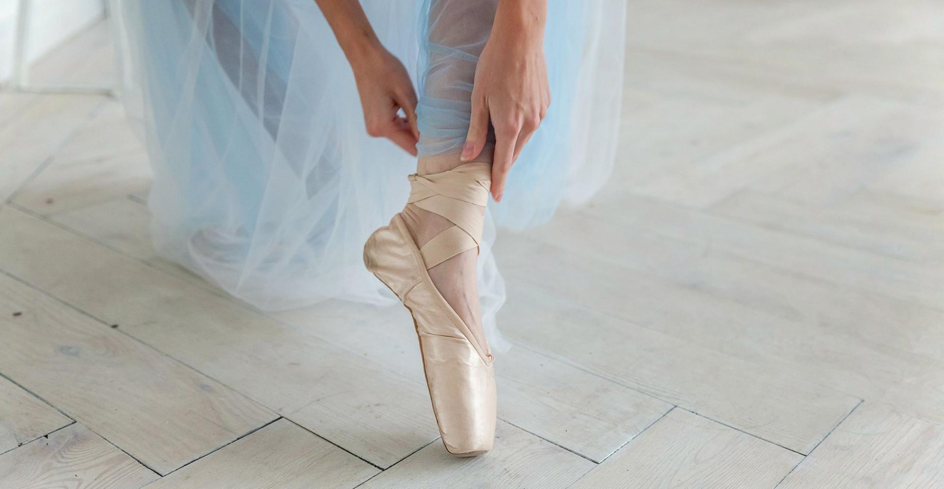 Eine Ballerina, die sich auf das Ballett vorbereitet, indem sie ihre Ballettschuhe anzieht